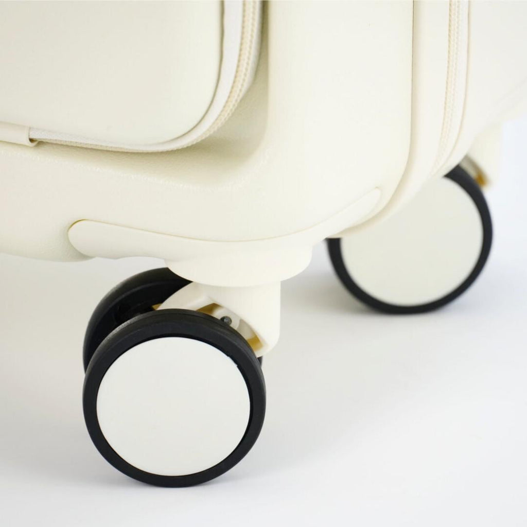 Close-up of the white carry-on suitcase corner and paired spinner wheels with black tires