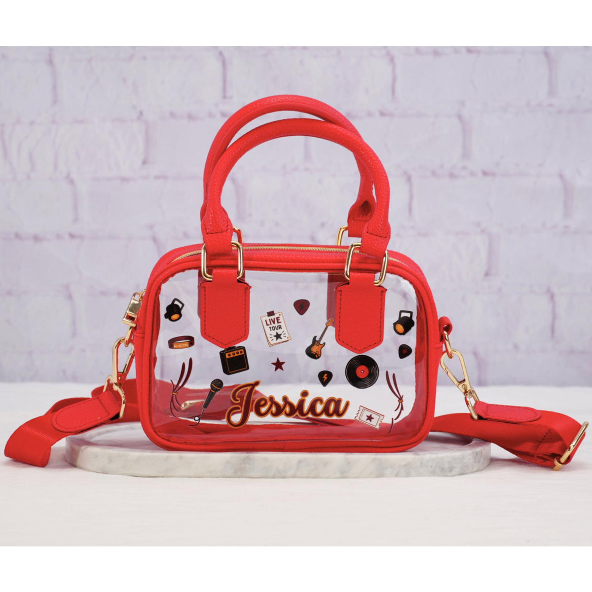 Clear stadium crossbody bag with red trim, matching strap and music graphics, personalized with example name Jessica