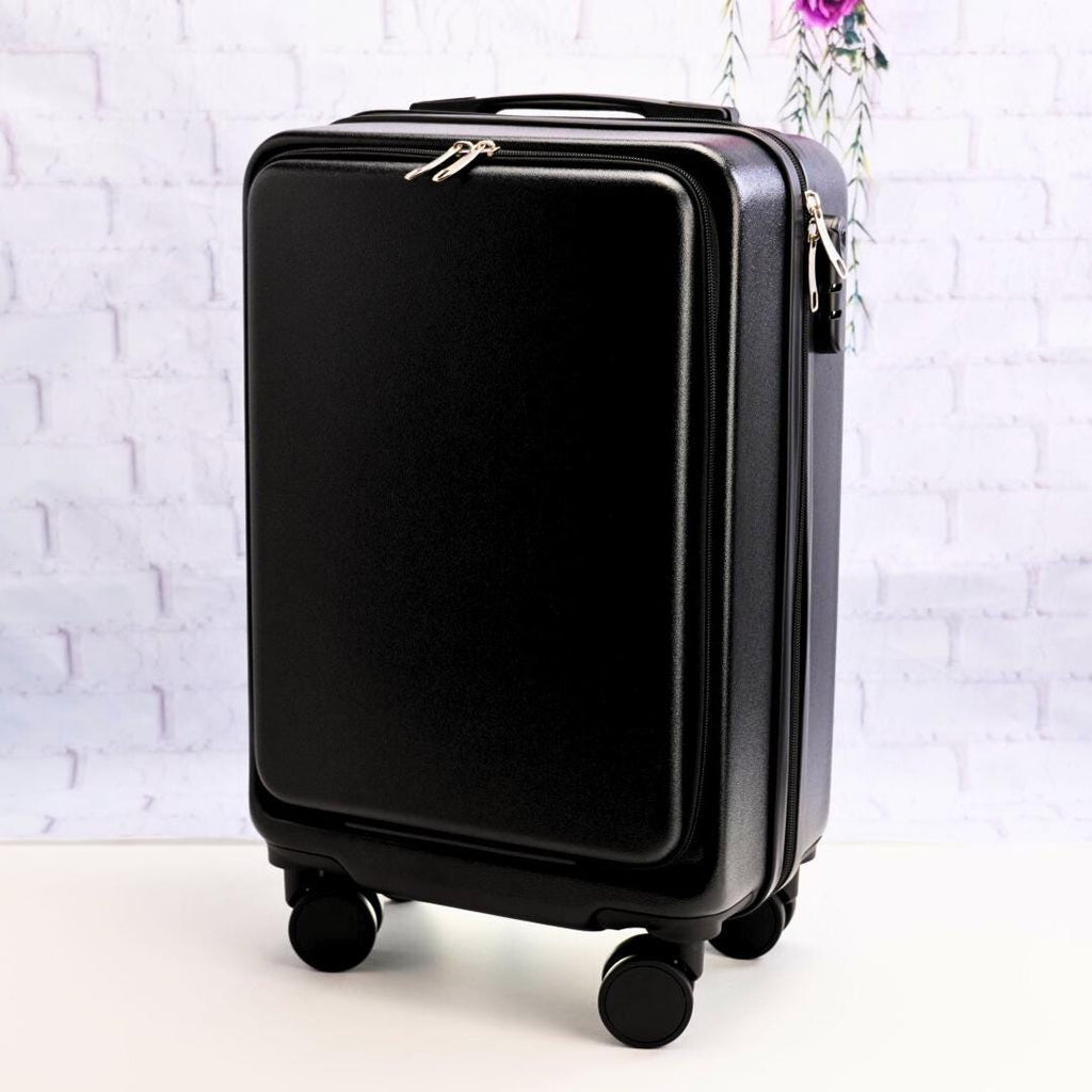 Angled front view of a plain black carry-on suitcase showing the zippered front panel, top handle and spinner wheels