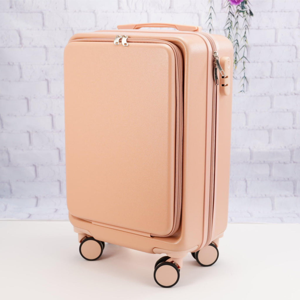 Angled front view of a plain pale pink carry-on suitcase showing the zippered front panel, top handle and spinner wheels