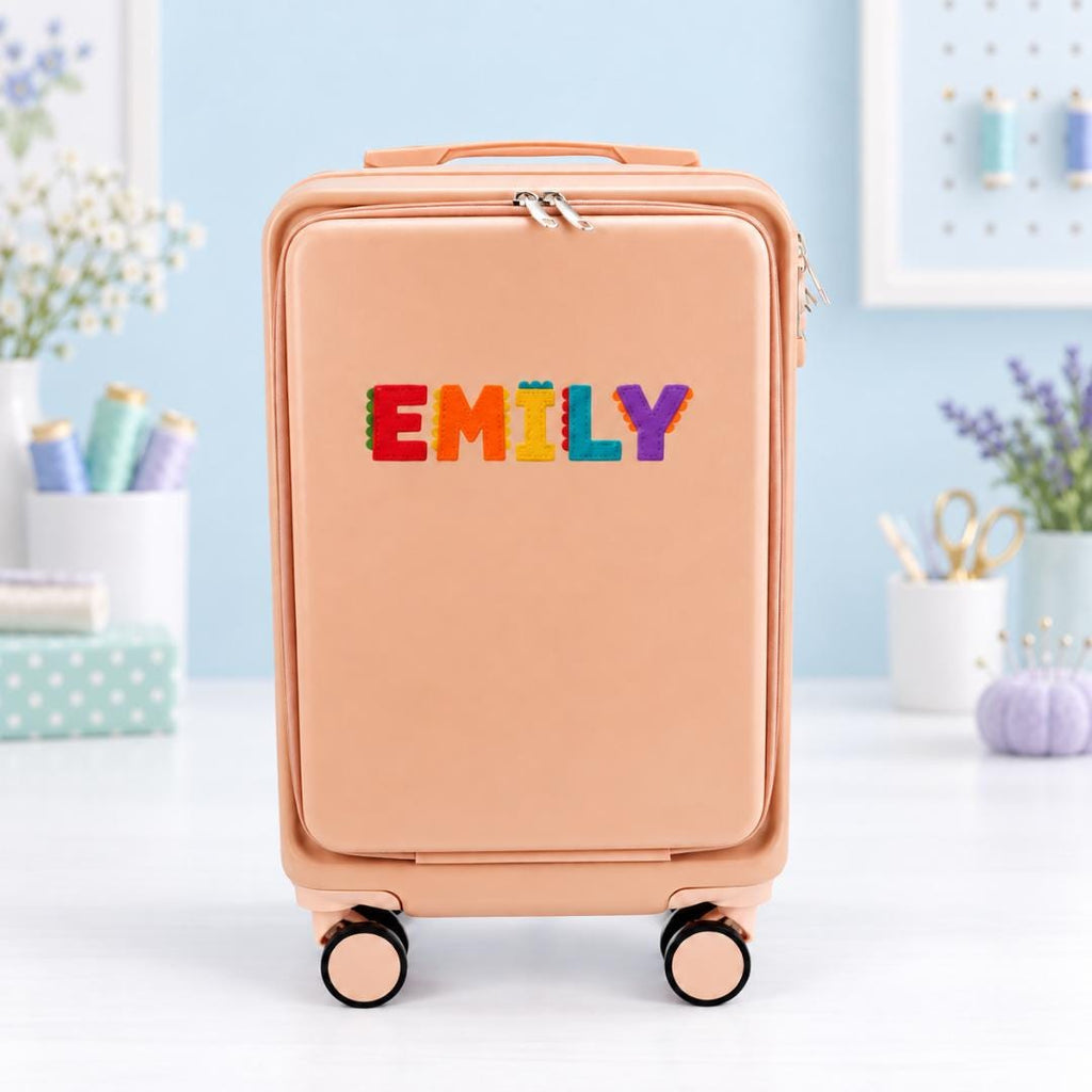 Pale pink personalized carry-on suitcase with example name Emily in multicolored block lettering