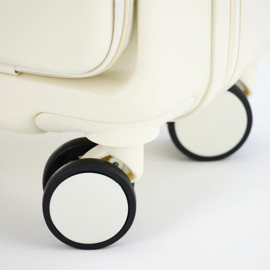 Close-up of the white carry-on suitcase corner and paired spinner wheels with black tires