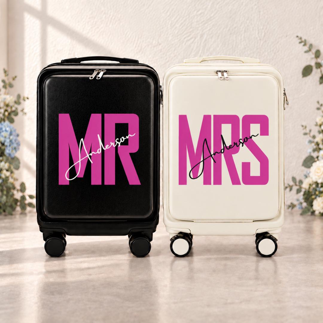 Black Mr and white Mrs carry-on suitcases with bright magenta lettering and an example personalized surname in script