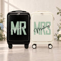Black Mr and white Mrs carry-on suitcases with mint green lettering and an example personalized surname in script