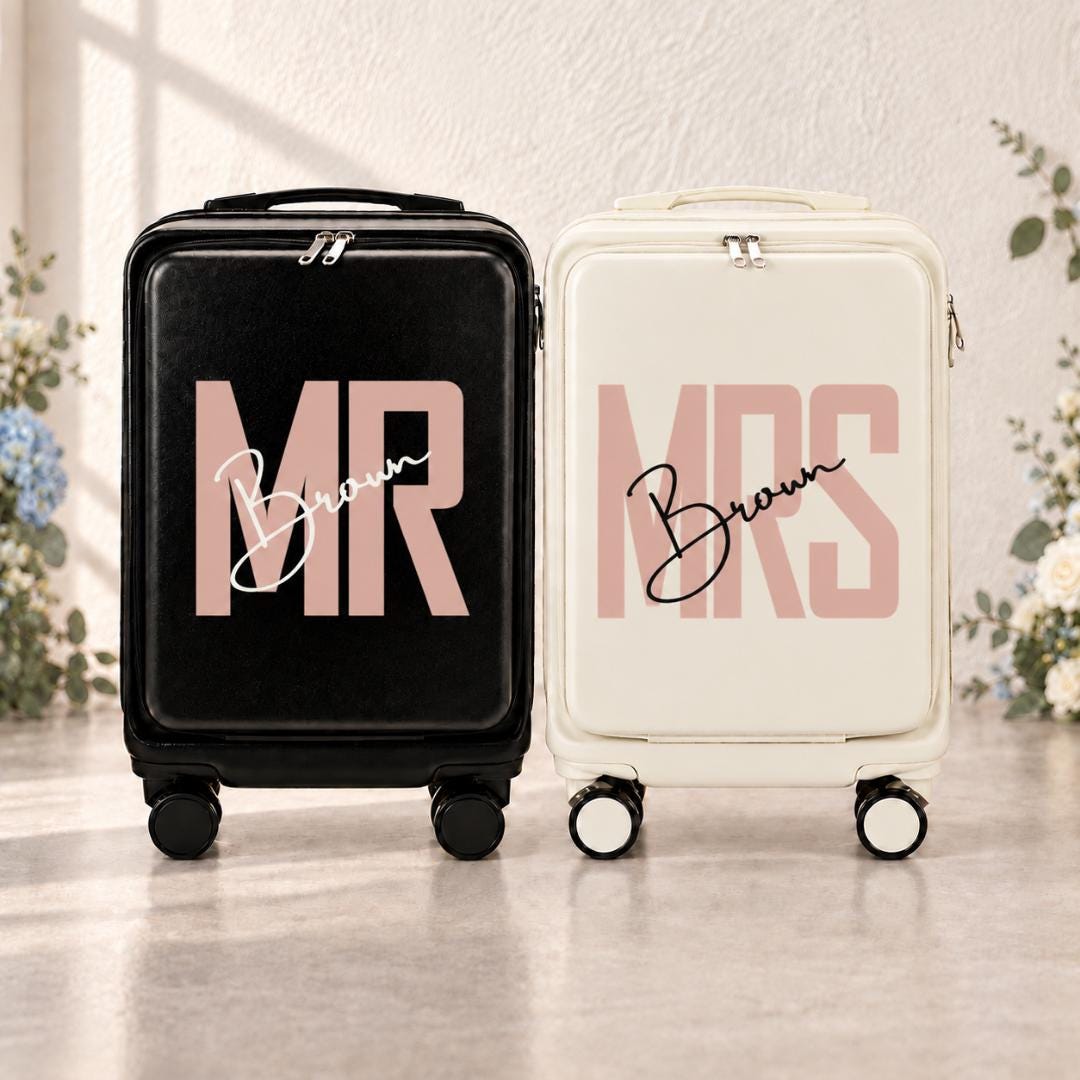 Black Mr and white Mrs carry-on suitcases with blush pink lettering and example surname Brown in script